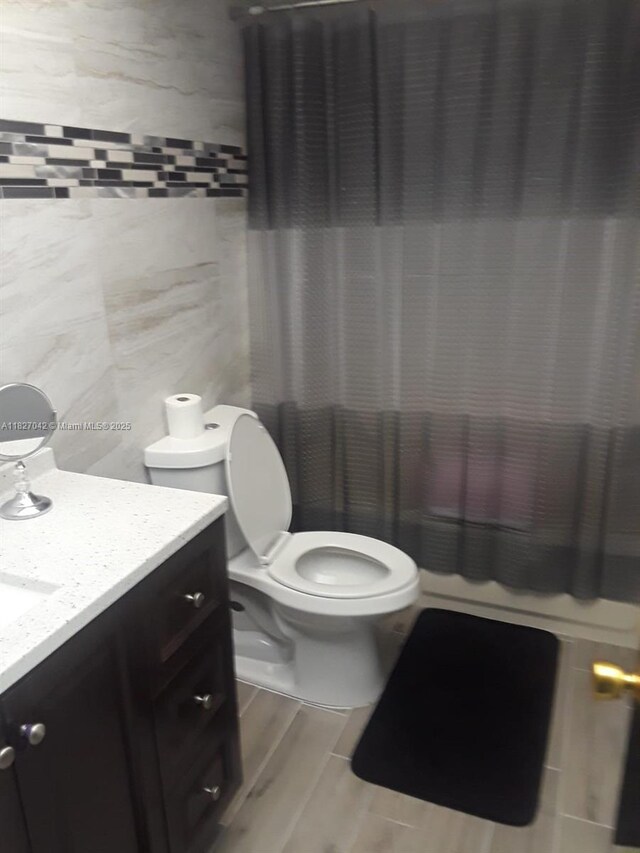 900 NE 12th Ave Unit 302, Hallandale Beach, FL 33009 - bathroom featuring vanity, tile walls, wood finished floors, and a shower with shower curtain