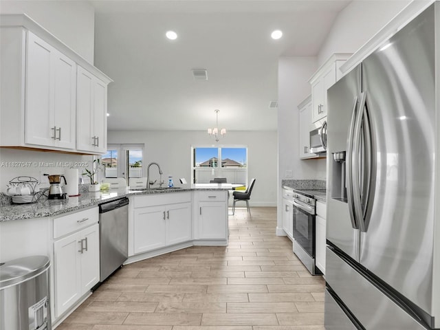 2405 Nelson Rd, Cape Coral, FL 33993 - kitchen with appliances with stainless steel finishes, a peninsula, light wood-type flooring, white cabinets, and a chandelier