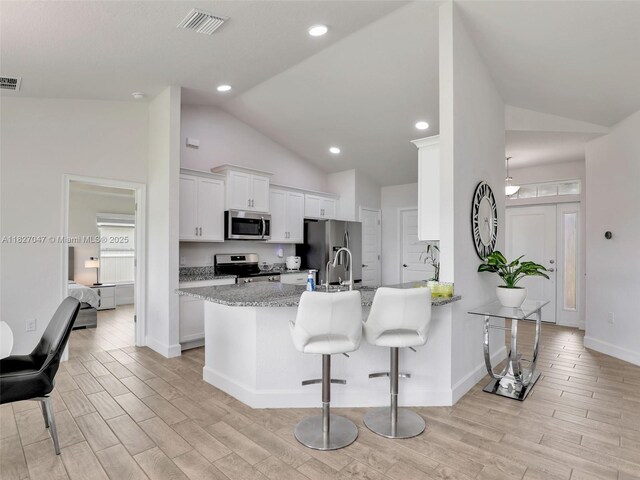 2405 Nelson Rd, Cape Coral, FL 33993 - kitchen featuring appliances with stainless steel finishes, light wood-style floors, a peninsula, a breakfast bar area, and white cabinetry