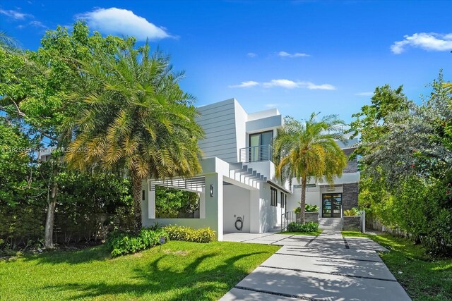 1311 Stillwater Dr, Miami Beach, FL 33141 - view of front of home with stucco siding, a balcony, a front lawn, and concrete driveway
