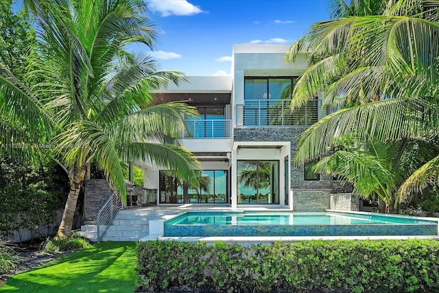 1311 Stillwater Dr, Miami Beach, FL 33141 - back of property featuring a balcony, an outdoor pool, stucco siding, stone siding, and a patio area