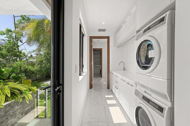 1311 Stillwater Dr, Miami Beach, FL 33141 - laundry area with estacked washer and dryer, light marble finish floors, and healthy amount of natural light