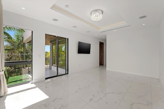 1311 Stillwater Dr, Miami Beach, FL 33141 - empty room featuring a chandelier, a tray ceiling, a smoke detector, and marble finish flooring