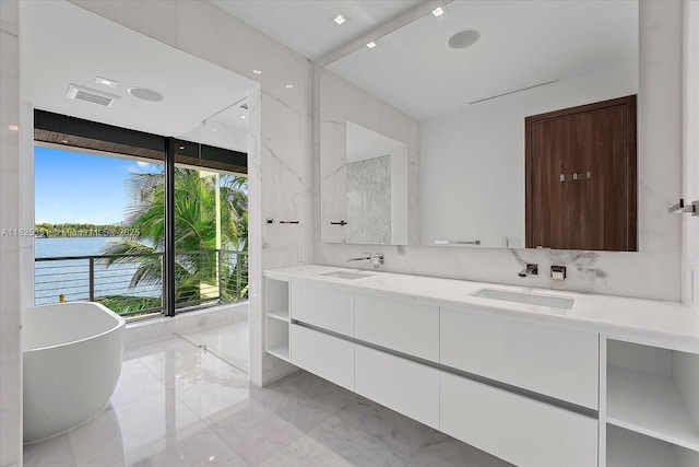 1311 Stillwater Dr, Miami Beach, FL 33141 - bathroom with double vanity, a soaking tub, and marble tiled floors