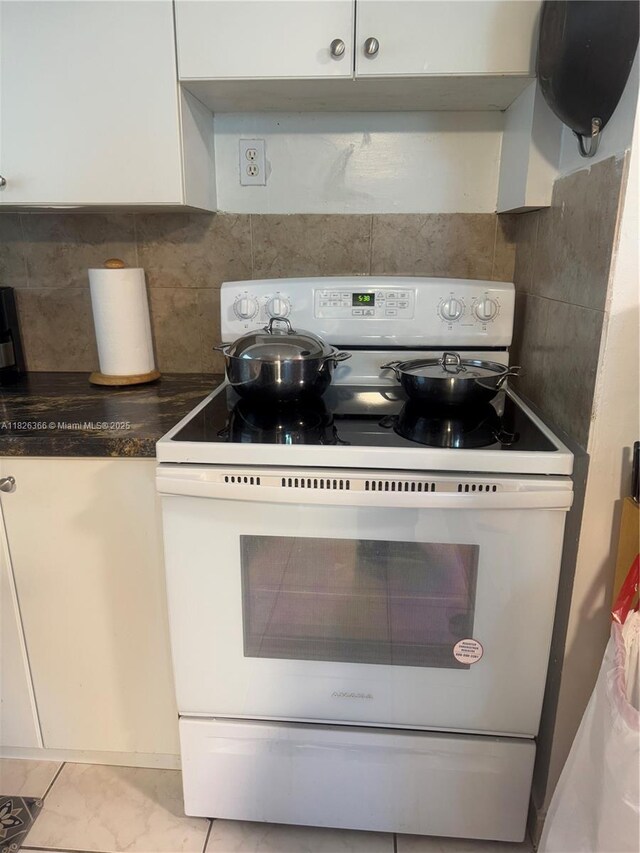 8821 W Flagler St Unit 108, Miami, FL 33174 - kitchen with white range with electric stovetop, decorative backsplash, dark countertops, and white cabinetry