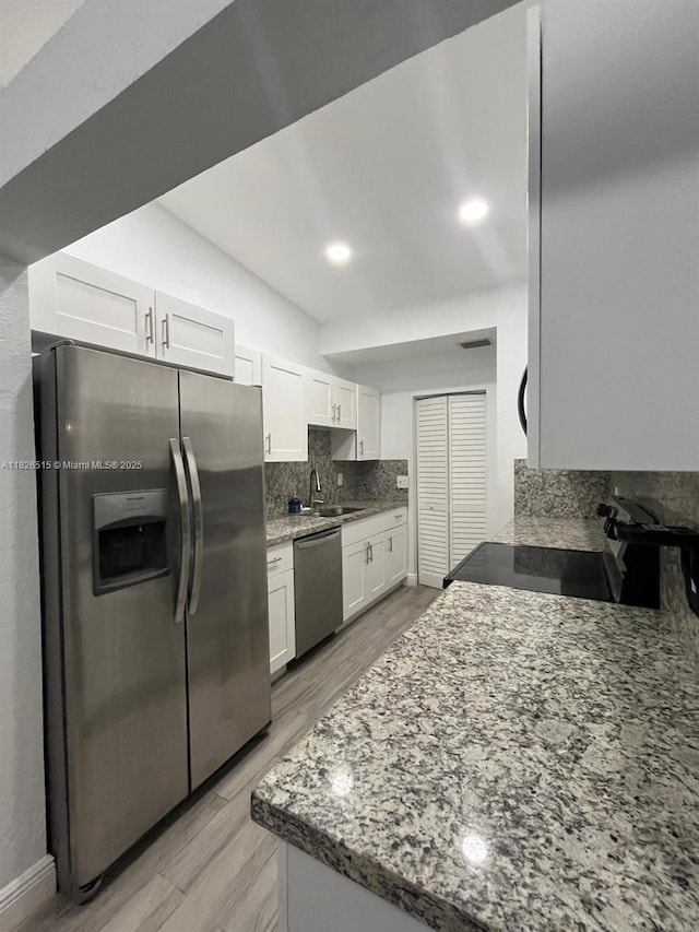 1710 NW 92nd Ave, Pembroke Pines, FL 33024 - kitchen with appliances with stainless steel finishes, decorative backsplash, white cabinets, light wood finished floors, and light stone counters
