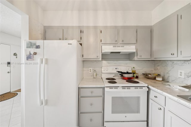 13450 SW 3rd St Unit 408D, Pembroke Pines, FL 33027 - kitchen featuring white appliances, under cabinet range hood, light countertops, tasteful backsplash, and light tile patterned flooring