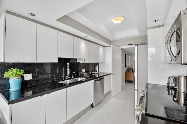 7000 Island Blvd Unit 1408, Aventura, FL 33160 - kitchen featuring appliances with stainless steel finishes, a raised ceiling, white cabinetry, decorative backsplash, and light tile patterned flooring