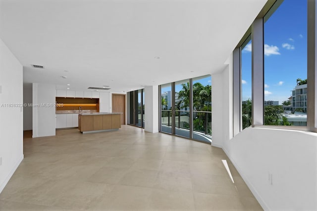 1135 103rd St Unit 408, Bay Harbor Islands, FL 33154 - unfurnished living room featuring a wall of windows and baseboards
