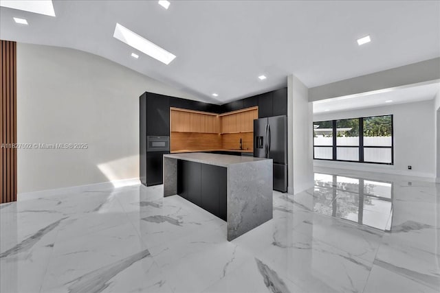 5890 SW 13th St, Plantation, FL 33317 - kitchen with stainless steel fridge, modern cabinets, a kitchen island, light countertops, and a skylight
