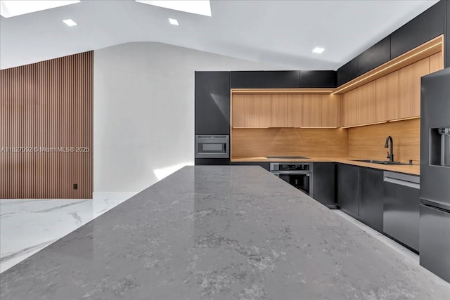 5890 SW 13th St, Plantation, FL 33317 - kitchen featuring stainless steel appliances, modern cabinets, lofted ceiling, light stone counters, and a skylight