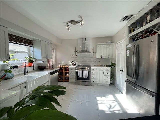 759 NE 87th St, Miami, FL 33138 - kitchen featuring stainless steel appliances, wall chimney range hood, tasteful backsplash, light tile patterned floors, and light countertops