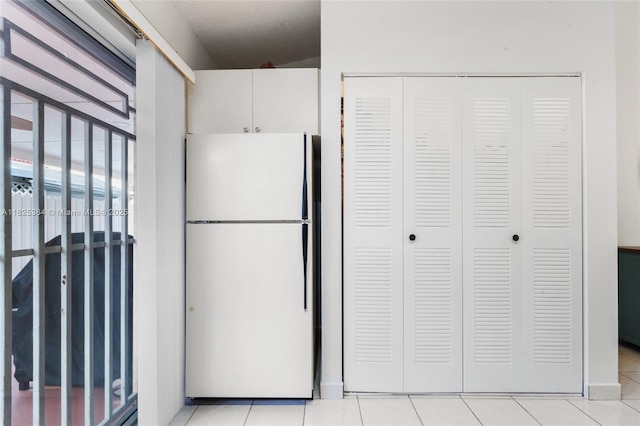 7101 W 24th Ave Unit 27, Hialeah, FL 33016 - kitchen featuring freestanding refrigerator, light tile patterned floors, and white cabinetry