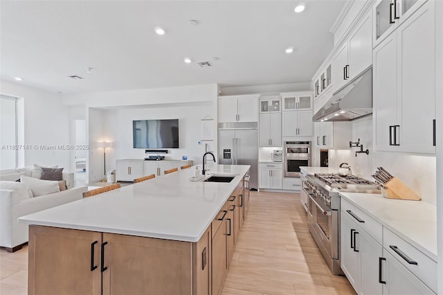 20161 SE Bridgewater Dr, Jupiter, FL 33458 - kitchen featuring high quality appliances, under cabinet range hood, open floor plan, glass insert cabinets, and a kitchen island with sink