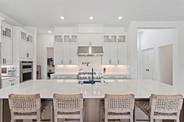 20161 SE Bridgewater Dr, Jupiter, FL 33458 - kitchen featuring under cabinet range hood, stainless steel double oven, light countertops, a spacious island, and tasteful backsplash