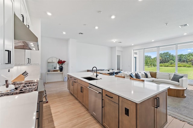 20161 SE Bridgewater Dr, Jupiter, FL 33458 - kitchen featuring appliances with stainless steel finishes, under cabinet range hood, open floor plan, a center island with sink, and brown cabinetry