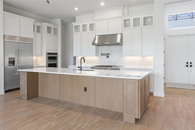 20161 SE Bridgewater Dr, Jupiter, FL 33458 - kitchen with appliances with stainless steel finishes, extractor fan, a large island, light wood-style flooring, and light countertops