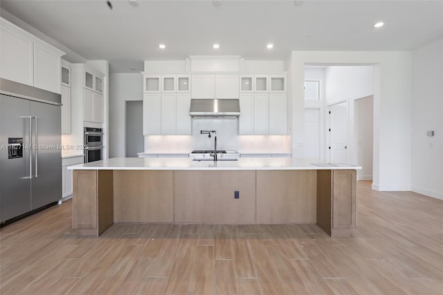20161 SE Bridgewater Dr, Jupiter, FL 33458 - kitchen with stainless steel appliances, range hood, a spacious island, light wood-type flooring, and recessed lighting