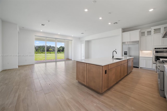20161 SE Bridgewater Dr, Jupiter, FL 33458 - kitchen with appliances with stainless steel finishes, open floor plan, light wood-type flooring, a center island with sink, and light countertops