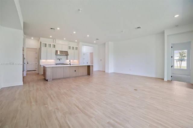 20161 SE Bridgewater Dr, Jupiter, FL 33458 - kitchen featuring under cabinet range hood, open floor plan, an island with sink, light countertops, and light wood finished floors