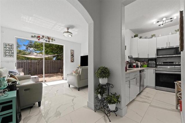 3818 SW 171st Ter, Miramar, FL 33027 - kitchen featuring stainless steel appliances, arched walkways, light marble finish flooring, white cabinets, and light countertops
