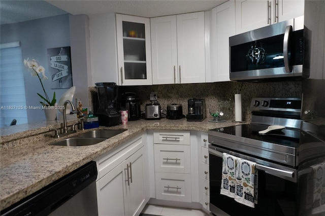 8215 SW 152nd Ave Unit G-307, Miami, FL 33193 - kitchen with appliances with stainless steel finishes, white cabinetry, light stone countertops, glass insert cabinets, and a textured ceiling