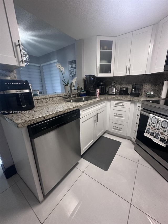8215 SW 152nd Ave Unit G-307, Miami, FL 33193 - kitchen featuring stainless steel dishwasher, a textured ceiling, white cabinetry, light tile patterned floors, and glass insert cabinets