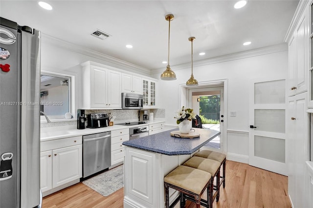 6731 SW 138th St, Palmetto Bay, FL 33158 - kitchen with stainless steel appliances, a breakfast bar area, white cabinets, ornamental molding, and light wood-style flooring