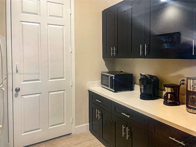 2009 SE 10th Ave Unit 318, Fort Lauderdale, FL 33316 - kitchen featuring black microwave, light countertops, dark cabinetry, and light wood-style floors