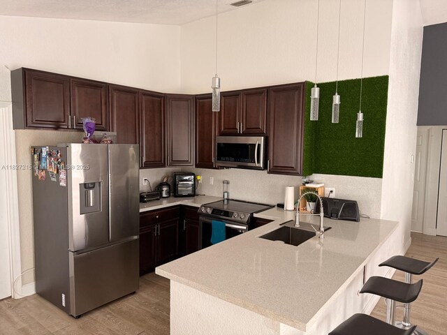 763 S Wind Cir, Sunrise, FL 33326 - kitchen featuring appliances with stainless steel finishes, a peninsula, light countertops, dark brown cabinetry, and light wood-style flooring