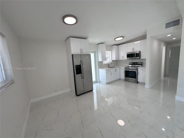 3231 NW 48th Ter, Miami, FL 33142 - kitchen featuring stainless steel appliances, light marble finish flooring, light countertops, and white cabinetry