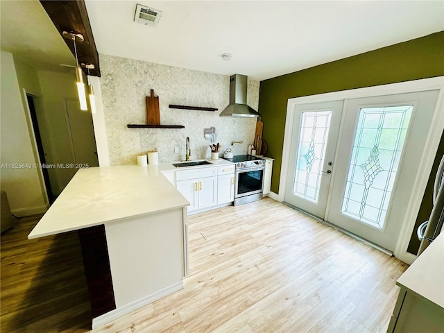 305 SW 24th Ave, Fort Lauderdale, FL 33312 - kitchen with wall chimney range hood, stainless steel range with electric stovetop, a peninsula, light countertops, and light wood-type flooring