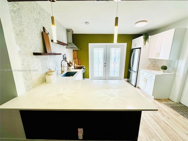 305 SW 24th Ave, Fort Lauderdale, FL 33312 - kitchen with wall chimney exhaust hood, freestanding refrigerator, french doors, a peninsula, and light countertops