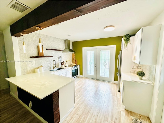 305 SW 24th Ave, Fort Lauderdale, FL 33312 - kitchen with wall chimney range hood, white cabinetry, light countertops, french doors, and stainless steel appliances