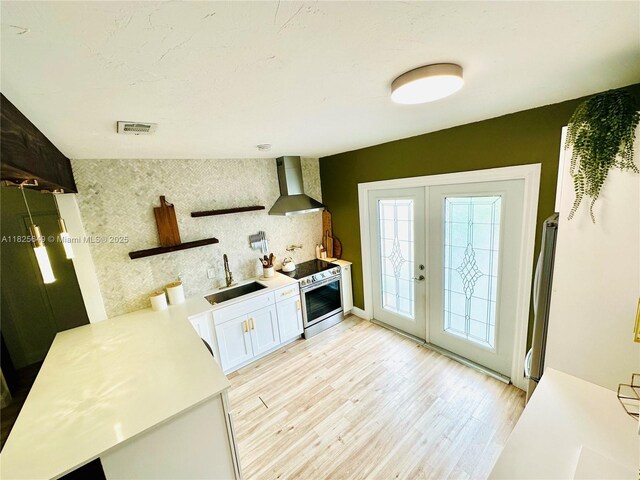 305 SW 24th Ave, Fort Lauderdale, FL 33312 - kitchen featuring wall chimney exhaust hood, open shelves, french doors, light wood finished floors, and white cabinets