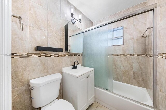 12995 NE 5th Ave, North Miami, FL 33161 - bathroom featuring bath / shower combo with glass door, tile walls, vanity, and tile patterned floors