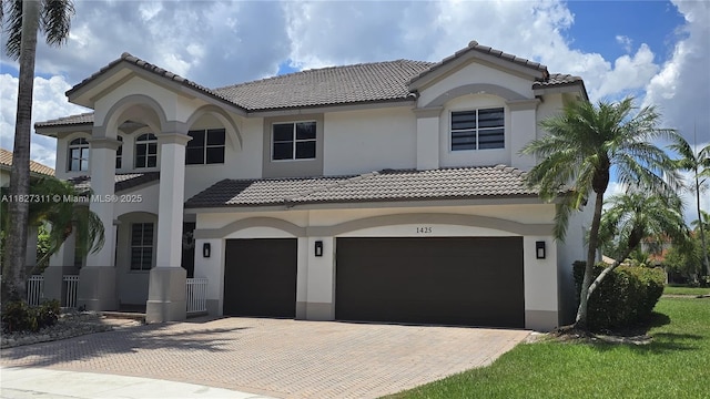 1425 Crossbill Ct, Weston, FL 33327 - mediterranean / spanish-style home featuring an attached garage, a tiled roof, stucco siding, and decorative driveway