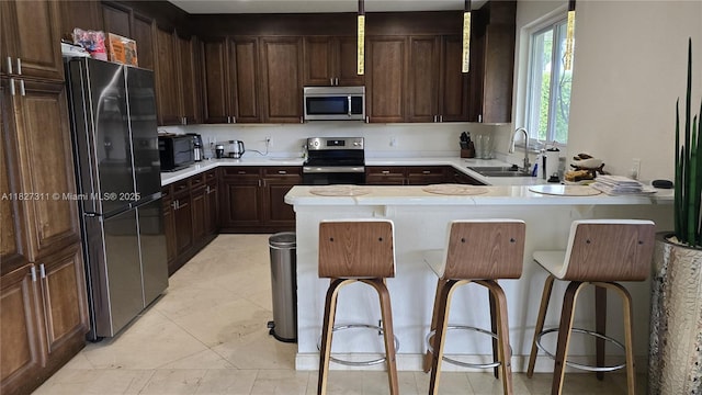1425 Crossbill Ct, Weston, FL 33327 - kitchen featuring appliances with stainless steel finishes, light countertops, dark brown cabinetry, a peninsula, and a breakfast bar area