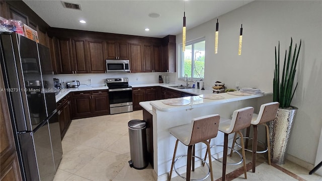 1425 Crossbill Ct, Weston, FL 33327 - kitchen with stainless steel appliances, a peninsula, dark brown cabinets, a kitchen bar, and light countertops