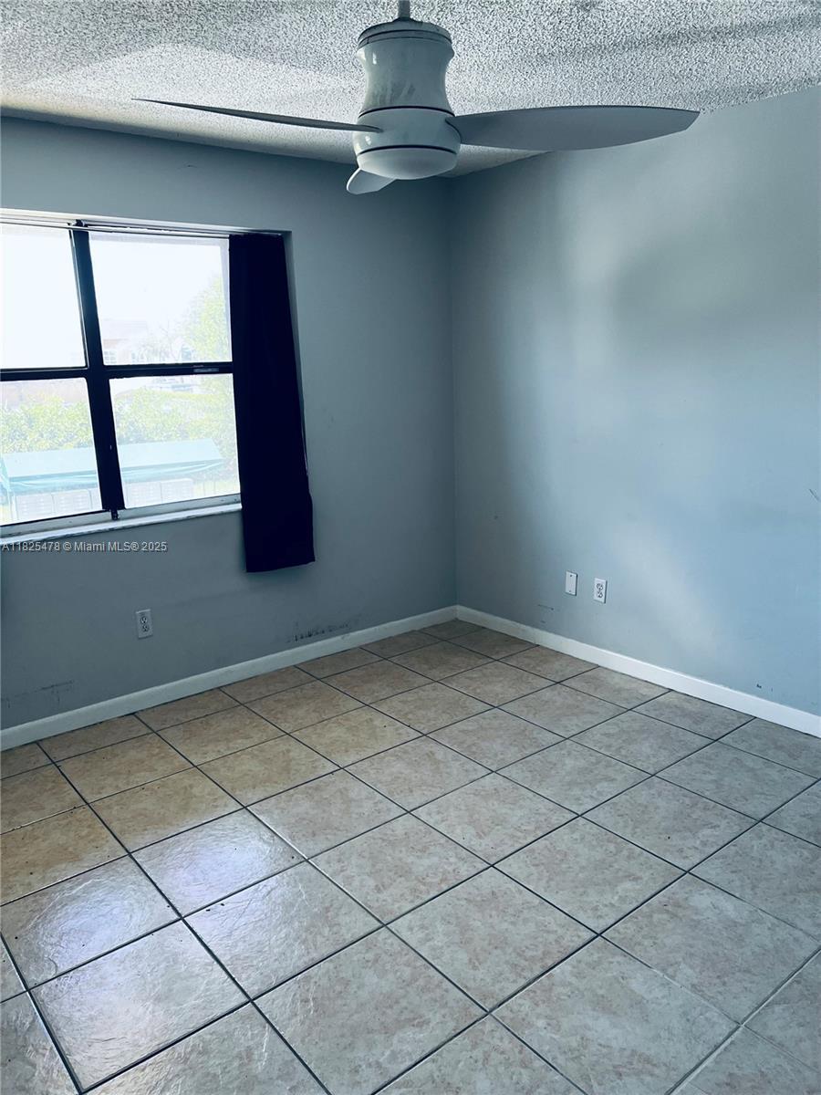 7670 SW 152nd Ave Unit 1-202, Miami, FL 33193 - unfurnished room featuring a textured ceiling, light tile patterned flooring, and a ceiling fan