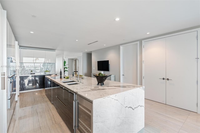 10203 Collins Ave Unit 1603, Bal Harbour, FL 33154 - kitchen featuring modern cabinets, a large island with sink, recessed lighting, light stone counters, and white cabinetry
