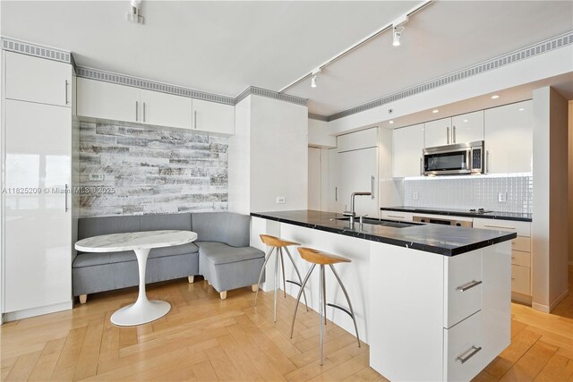 50 Biscayne Blvd Unit 3002, Miami, FL 33132 - kitchen featuring stainless steel microwave, rail lighting, dark countertops, white cabinets, and a peninsula