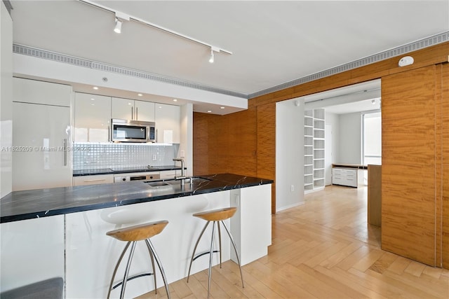 50 Biscayne Blvd Unit 3002, Miami, FL 33132 - kitchen with stainless steel microwave, dark countertops, a breakfast bar area, white cabinets, and rail lighting