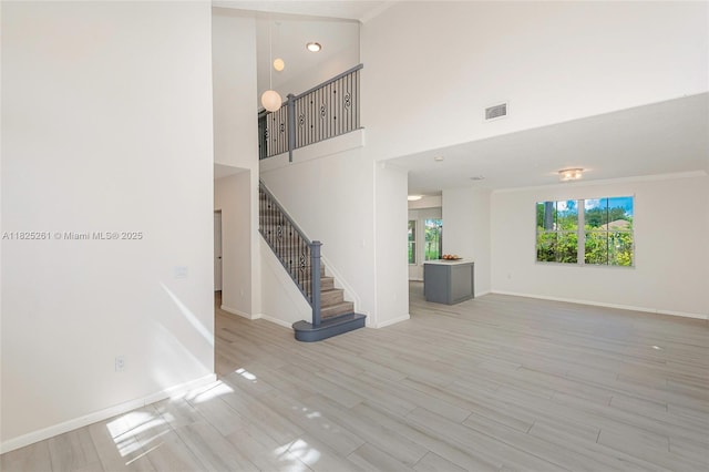 315 W Cypress Cove Cir, Davie, FL 33325 - unfurnished living room with light wood-style floors, stairs, a high ceiling, and ornamental molding