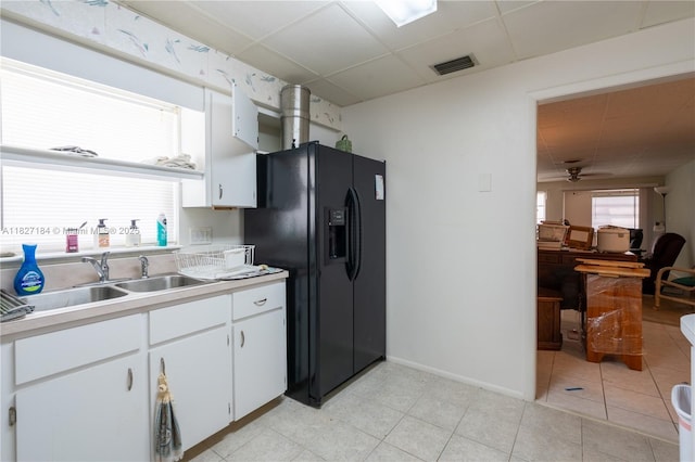 3126 Harbor Blvd Unit 1A, Port Charlotte, FL 33952 - kitchen with a paneled ceiling, ceiling fan, light countertops, black fridge with ice dispenser, and white cabinets