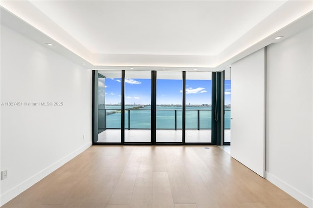 3131 NE 7th Ave Unit 2705, Miami, FL 33137 - empty room featuring expansive windows, a water view, wood finished floors, a tray ceiling, and recessed lighting