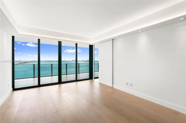 3131 NE 7th Ave Unit 2705, Miami, FL 33137 - empty room with a wall of windows, a tray ceiling, a water view, and light wood-style floors