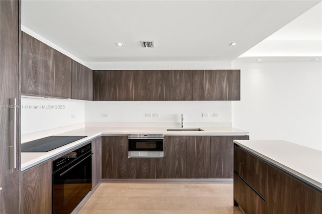 3131 NE 7th Ave Unit 2705, Miami, FL 33137 - kitchen featuring black appliances, modern cabinets, light countertops, dark brown cabinets, and recessed lighting