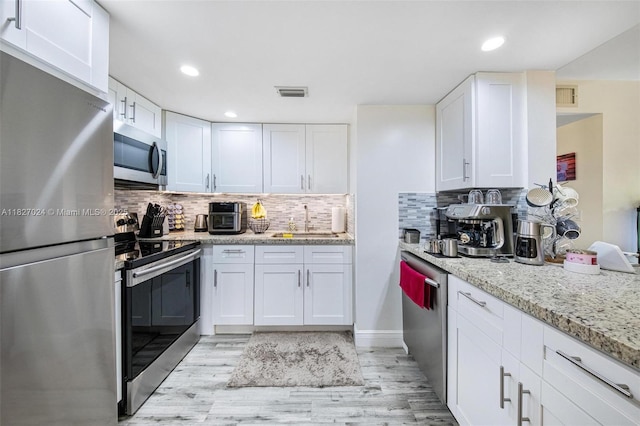 7925 SW 86th St Unit 903, Miami, FL 33143 - kitchen with stainless steel appliances, white cabinetry, light wood-style flooring, decorative backsplash, and recessed lighting