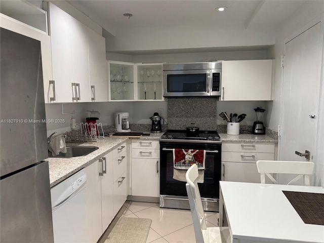 300 Bayview Dr Unit 1009, Sunny Isles Beach, FL 33160 - kitchen featuring stainless steel appliances, light tile patterned flooring, white cabinets, light stone countertops, and recessed lighting